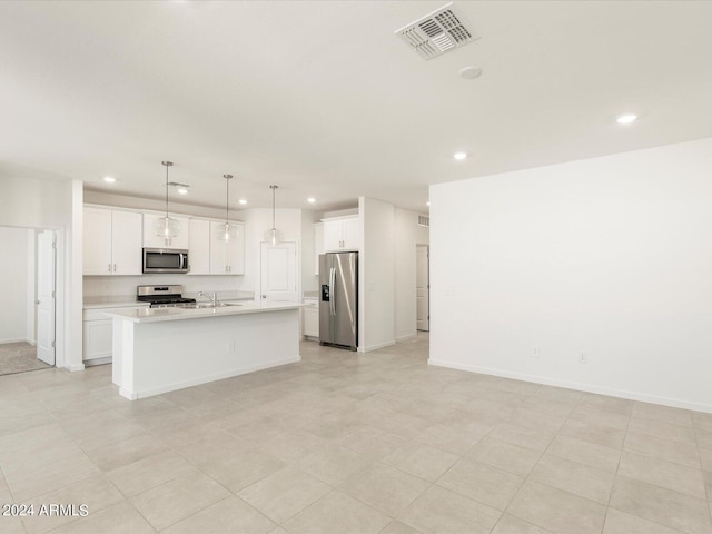 kitchen featuring appliances with stainless steel finishes, sink, an island with sink, hanging light fixtures, and white cabinetry