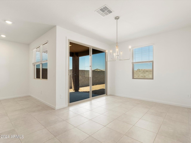 spare room with an inviting chandelier, plenty of natural light, and light tile patterned floors