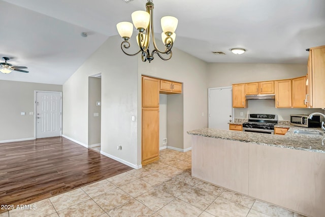 12441 W Windsor Blvd, Litchfield Park, AZ 85340 - kitchen with stainless steel gas range oven, vaulted ceiling, a peninsula, under cabinet range hood, and light stone countertops
