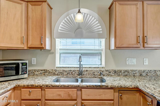 12441 W Windsor Blvd, Litchfield Park, AZ 85340 - kitchen with stainless steel microwave, a sink, light brown cabinets, light stone counters, and hanging light fixtures