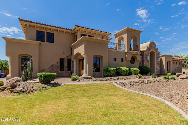 mediterranean / spanish house with a balcony and a front lawn