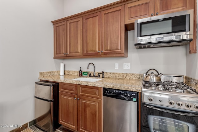 kitchen featuring light stone countertops, appliances with stainless steel finishes, and sink