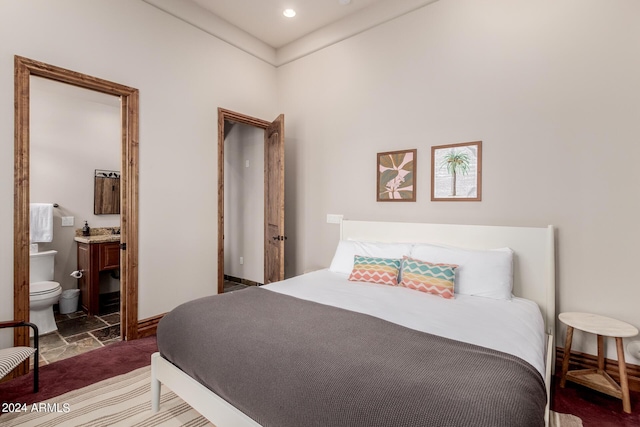 bedroom featuring ensuite bathroom and dark carpet