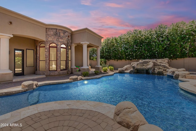 pool at dusk featuring pool water feature