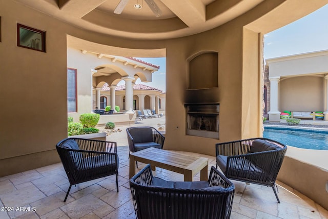 view of patio featuring ceiling fan and an outdoor fireplace