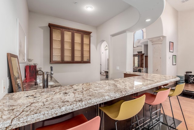 bar with hardwood / wood-style floors and light stone counters