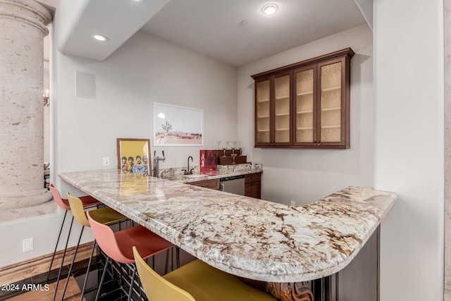 bar featuring light stone countertops, stainless steel dishwasher, and sink