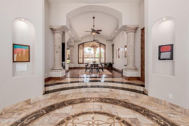 hall featuring ornate columns, a chandelier, and wood-type flooring