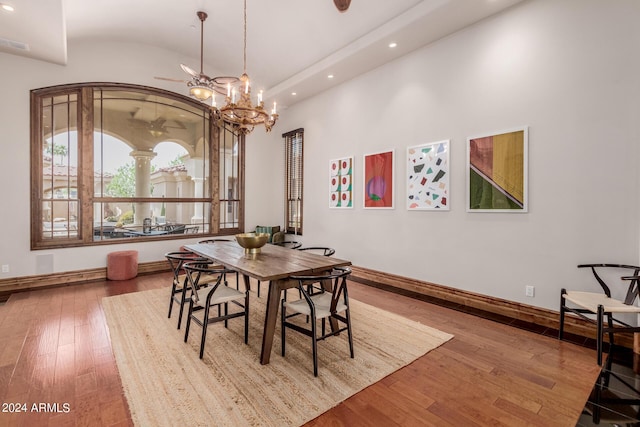 dining room featuring hardwood / wood-style flooring, lofted ceiling, and a chandelier