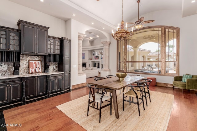 dining space with ceiling fan with notable chandelier, light wood-type flooring, and decorative columns