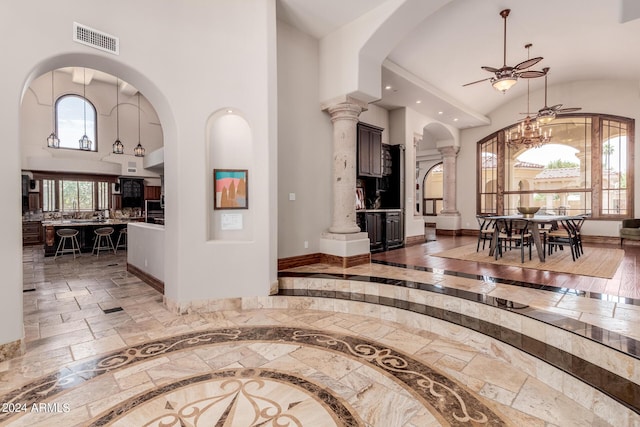 corridor featuring a towering ceiling and decorative columns