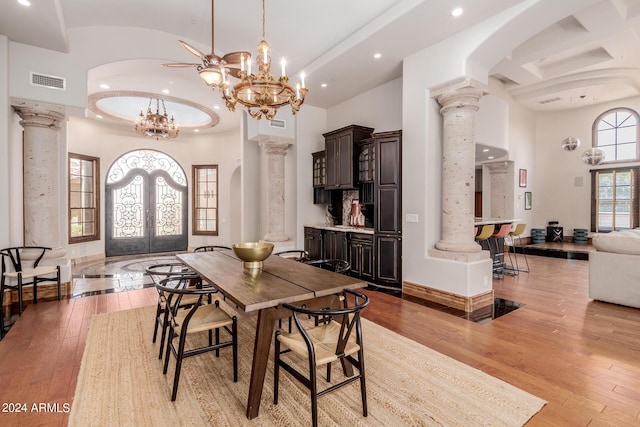 dining area featuring ornate columns, light hardwood / wood-style flooring, a towering ceiling, and french doors