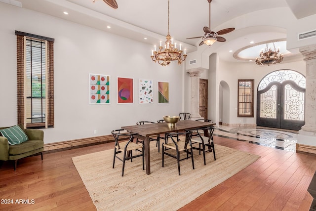 dining space featuring french doors, a towering ceiling, hardwood / wood-style flooring, and decorative columns