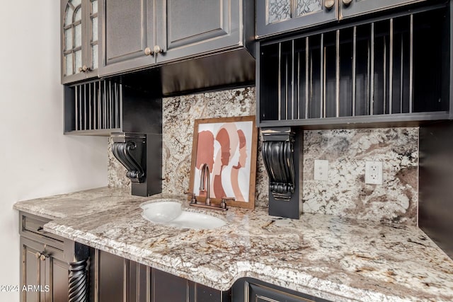 interior space with tasteful backsplash, light stone counters, and sink