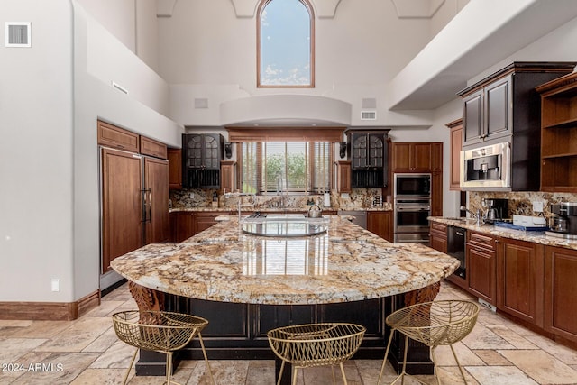 kitchen with built in appliances, a spacious island, a breakfast bar area, and tasteful backsplash