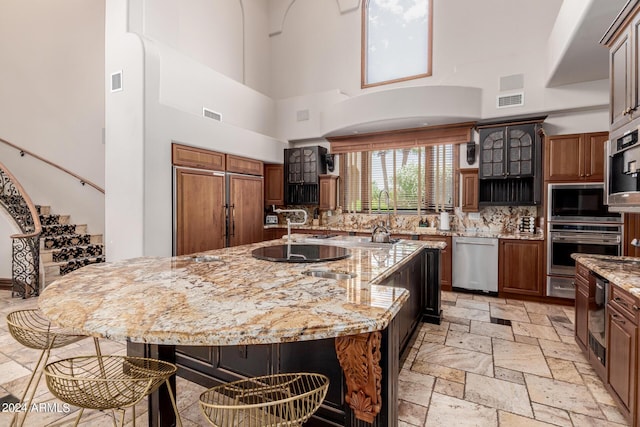 kitchen with a large island, a towering ceiling, and appliances with stainless steel finishes