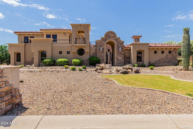 mediterranean / spanish-style house with a balcony and a front lawn