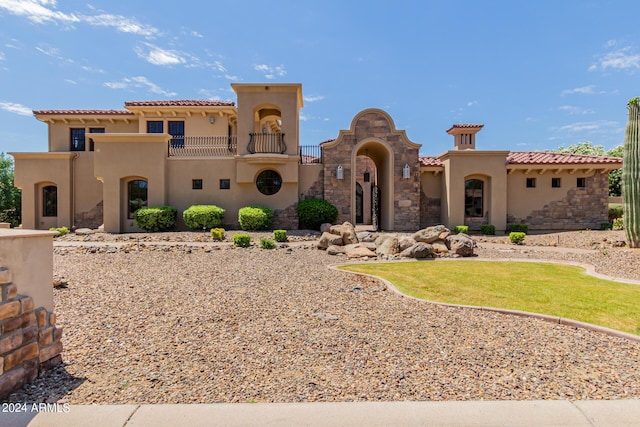 mediterranean / spanish-style house with a balcony and a front lawn