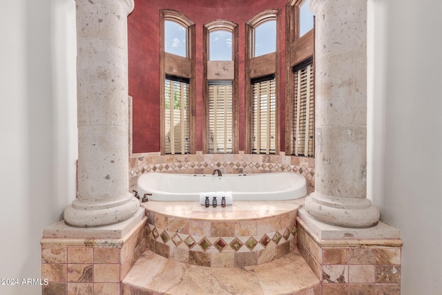 bathroom featuring a relaxing tiled tub and ornate columns