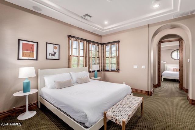 carpeted bedroom with a raised ceiling