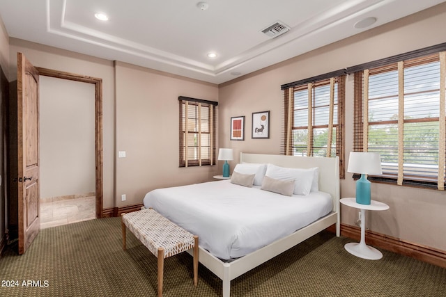 bedroom with carpet floors and a tray ceiling