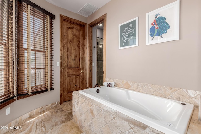 bathroom with plenty of natural light and tiled tub