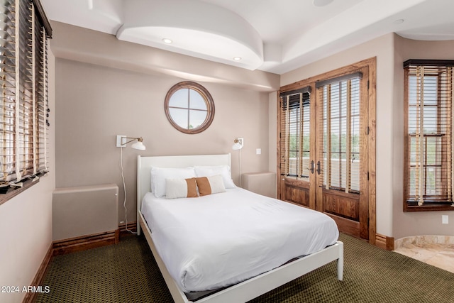 bedroom with multiple windows and dark colored carpet