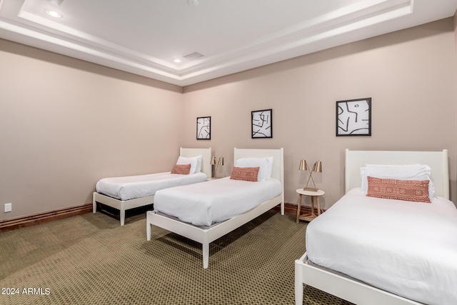 bedroom with carpet floors and a raised ceiling