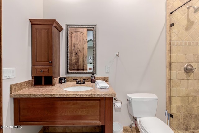 bathroom with a tile shower, vanity, and toilet