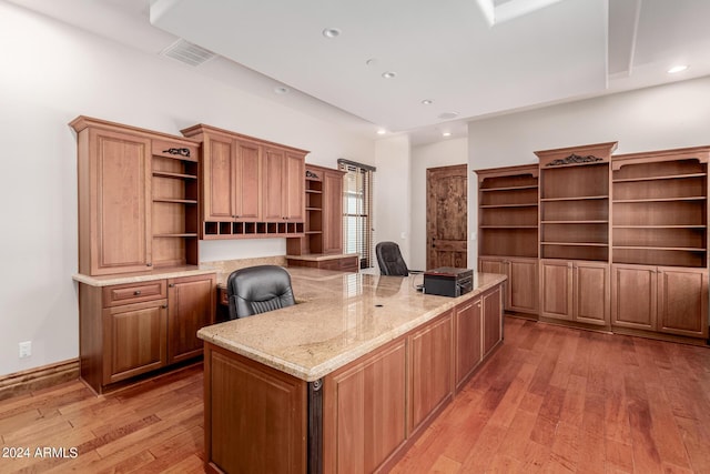 unfurnished office featuring built in desk and light hardwood / wood-style floors