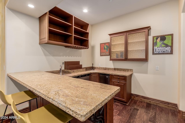 kitchen featuring a breakfast bar, dishwasher, dark wood-type flooring, sink, and kitchen peninsula