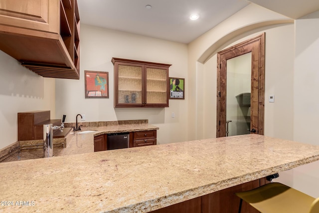 kitchen with stainless steel dishwasher, kitchen peninsula, and sink