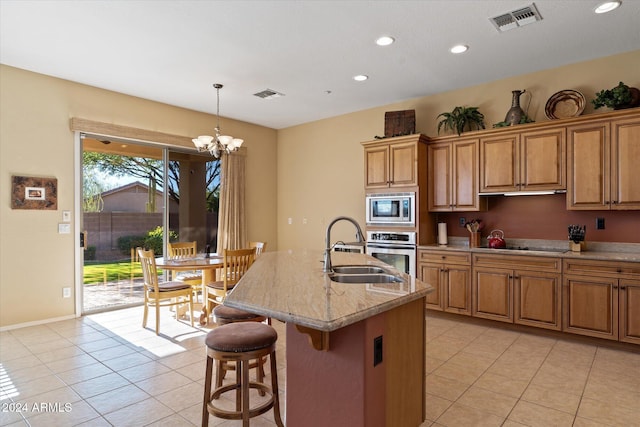 kitchen with pendant lighting, an inviting chandelier, a center island with sink, sink, and appliances with stainless steel finishes