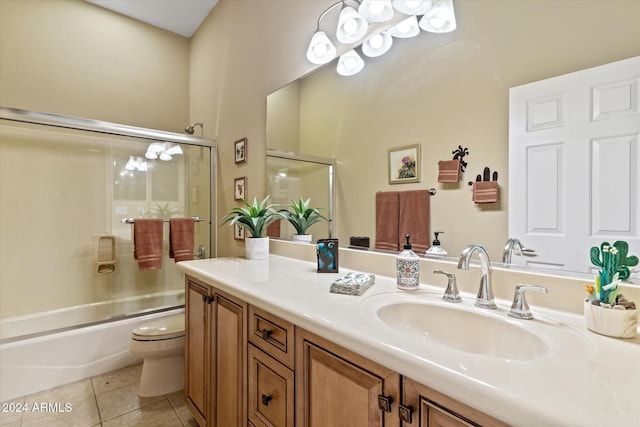 full bathroom with toilet, vanity, tile patterned floors, and bath / shower combo with glass door