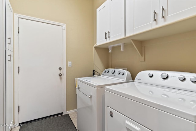 laundry area with washing machine and clothes dryer and cabinets