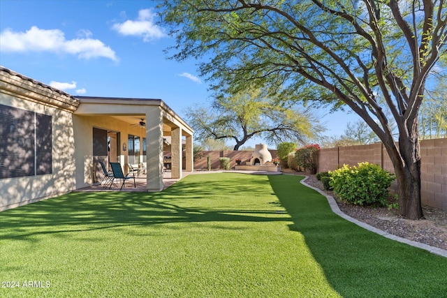 view of yard featuring ceiling fan, a patio, and exterior fireplace