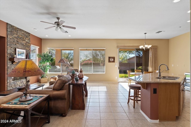 tiled living room featuring ceiling fan with notable chandelier, a wealth of natural light, and sink