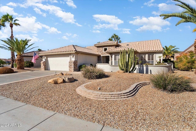 mediterranean / spanish home with stucco siding, concrete driveway, an attached garage, stone siding, and a tiled roof