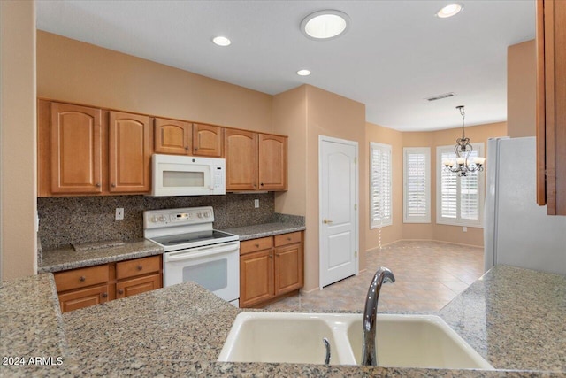 kitchen featuring a chandelier, white appliances, a sink, visible vents, and tasteful backsplash