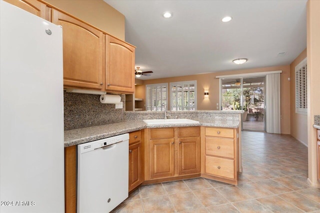 kitchen with tasteful backsplash, light countertops, a sink, white appliances, and a peninsula