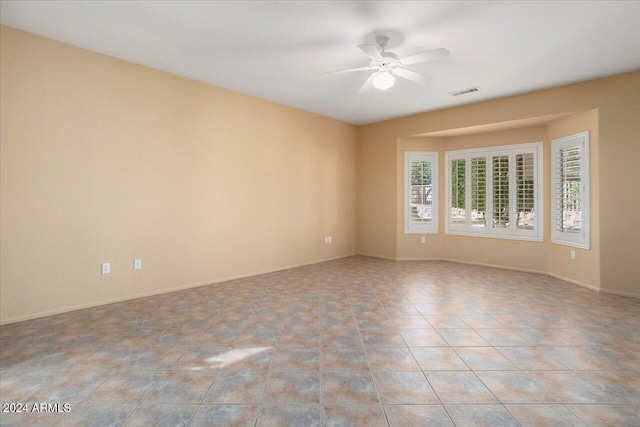 empty room featuring ceiling fan, light tile patterned floors, visible vents, and baseboards