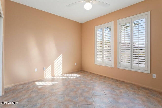 empty room featuring tile patterned flooring, ceiling fan, and baseboards