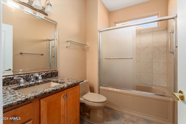 bathroom featuring toilet, bath / shower combo with glass door, and vanity