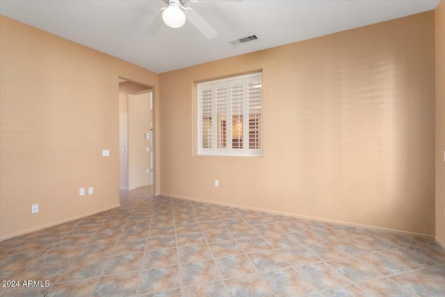 spare room with a ceiling fan, visible vents, and baseboards