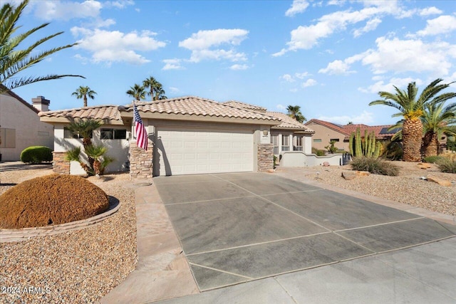 view of front facade with an attached garage, concrete driveway, stone siding, a tiled roof, and stucco siding