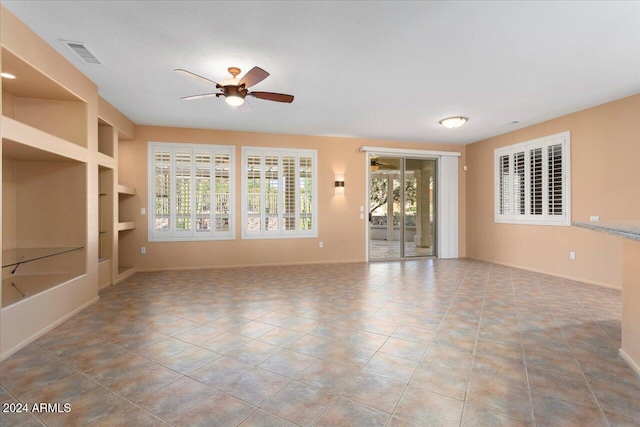 tiled empty room featuring baseboards, a ceiling fan, visible vents, and built in features