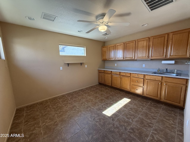 kitchen with light countertops, visible vents, a sink, and baseboards