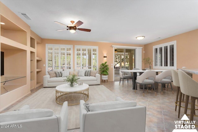 living room featuring built in shelves, visible vents, ceiling fan, and tile patterned floors