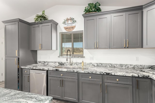 kitchen featuring stainless steel dishwasher, gray cabinetry, and vaulted ceiling