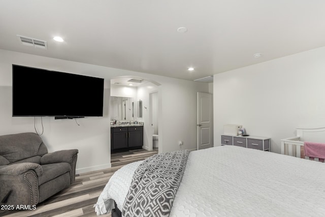 bedroom with connected bathroom and light wood-type flooring